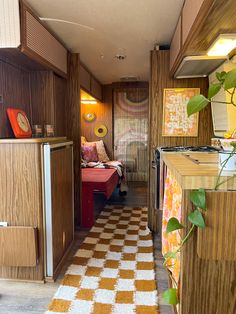 the inside of a camper with wood paneling and checkered rug on the floor