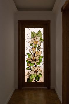 a stained glass door with flowers on it in a room that has wood floors and white walls