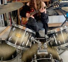 a woman sitting on top of a drum set