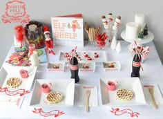 an assortment of desserts and snacks on a white table with red ribbon around the edges