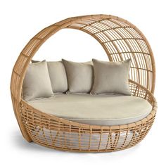 a wicker day bed with cushions and pillows on it's sides, in front of a white background