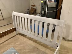 a white bed frame sitting on top of a hard wood floor next to a wall