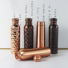 four different types of copper colored bottles lined up on a white surface with words above them