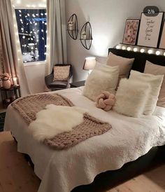 a bedroom with white bedding and lights on the window sill, wooden flooring