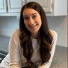 a woman with long hair is sitting in front of an oven and smiling at the camera