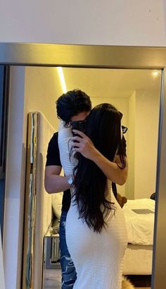 a man and woman taking a selfie in front of a mirror