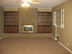 an empty living room with two windows and a ceiling fan in the middle of it