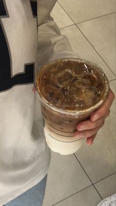 a person holding a cup of coffee with ice cream on top and brown liquid in it