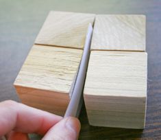 two pieces of wood being held together by a person's hand on a table