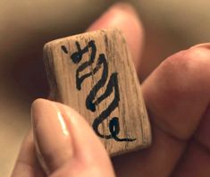 a person holding a wooden block with writing on it