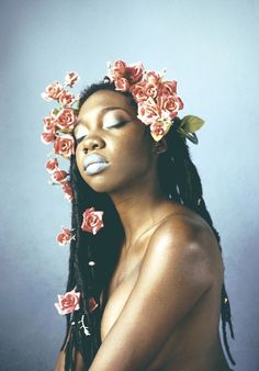 a woman with flowers in her hair is posing for the camera and has eyes closed