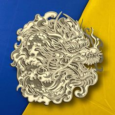 an intricately designed paper sculpture on a blue, yellow and yellow background with the image of a dragon's head