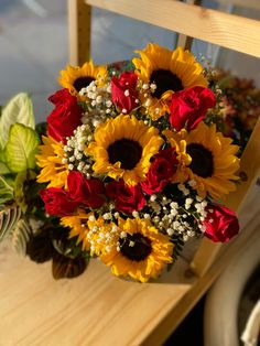 a bouquet of sunflowers and roses on a table