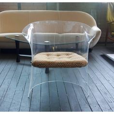 a glass coffee table with a foot stool in front of it on a wooden floor