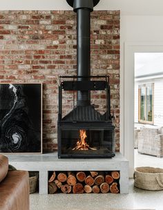 a living room with a fire place in the center and wood logs on the floor