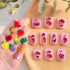 a person holding some fruit and veggies shaped cookie cutters in their hand