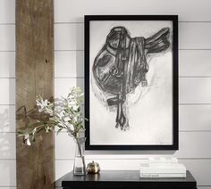 a black and white photo hanging on the wall next to a vase with flowers in it