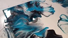 an abstract painting with blue, black and white colors on it's surface is shown