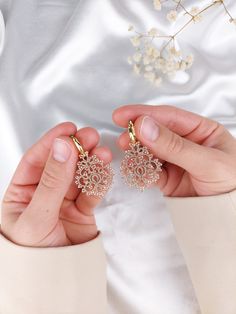 a person holding two pairs of earrings in their hands