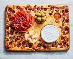 an appetizer board with cheese, meats and olives on it is shown