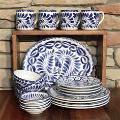 blue and white dinnerware on display in front of brick wall