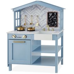 a blue toy kitchen with gold accessories on the counter top and an chalkboard behind it