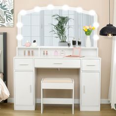 a white vanity table with stools and a mirror on the wall above it in a bedroom