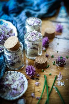 small jars filled with purple flowers on top of a wooden table