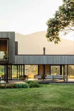 a modern house with glass walls and sliding doors on the outside, surrounded by lush green grass