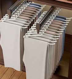 several folded towels hanging on a rack in front of a cabinet with wooden floors and drawers