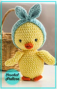 a crocheted chicken with a blue hat on it's head sitting next to a basket