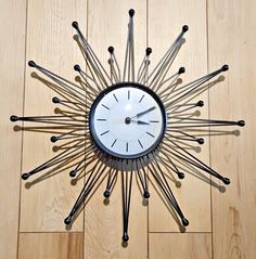 a clock that is on the floor with sticks sticking out of it's face