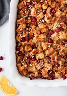 cranberry bread pudding in a white baking dish with orange slices on the side