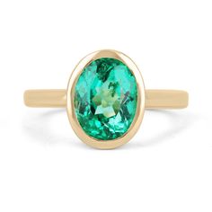 a gold ring with an oval cut green tourmaline stone in the center, on a white background