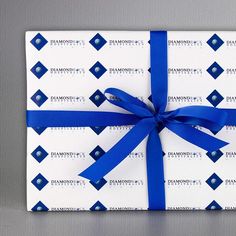 a gift wrapped in white and blue paper with a blue ribbon on it's side