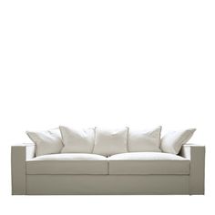 a white couch with four pillows on it's back and one arm facing the camera