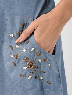 a woman's hand is holding an embroidered pocket