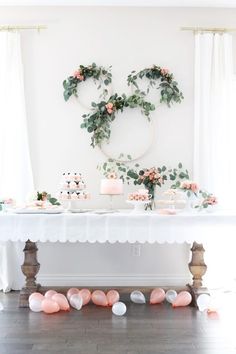 the table is decorated with pink and white flowers, greenery and cake on it