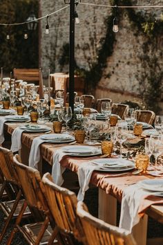 an outdoor dining table set up with place settings and plates for guests to sit at