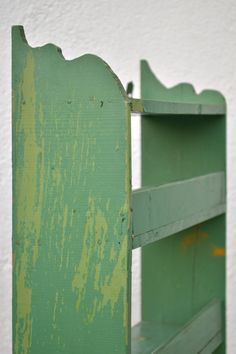 an old green painted wooden shelf against a white wall