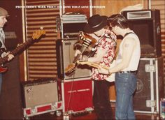 two young men are playing guitars in front of some speakers and amps on stage