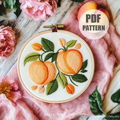 an embroidery pattern with peaches and leaves on it, next to some pink flowers