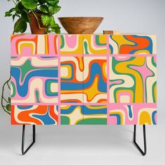 a multicolored cabinet with a potted plant sitting on it's side