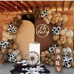 a baby shower is decorated with cow print balloons and decorations, including a wagon wheel