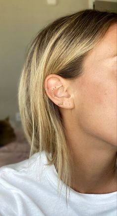 a close up of a person with ear piercings on their ears and wearing a white t - shirt