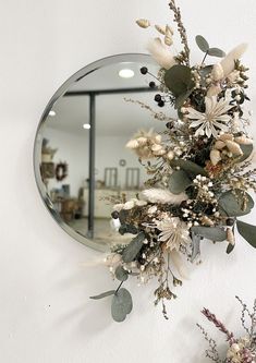 a mirror hanging on the wall with flowers in it