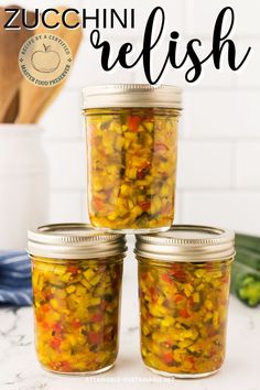 three jars filled with pickled vegetables sitting on top of a counter next to a wooden spoon