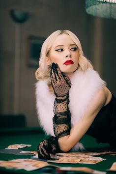 a woman in black and white is holding her hands up to her face while sitting on a pool table