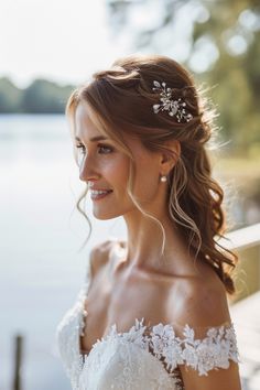 a woman wearing a white wedding dress standing next to a body of water with her hair in the air