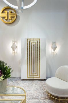 a living room filled with white furniture and gold accents on the walls, along with a round coffee table